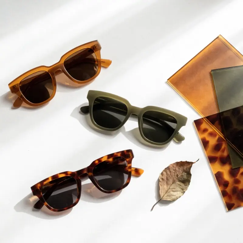 bio acetate sunglasses sustainable eyewear brand — amber olive and tortoiseshell frames beside plant-based acetate sheet samples and botanical element