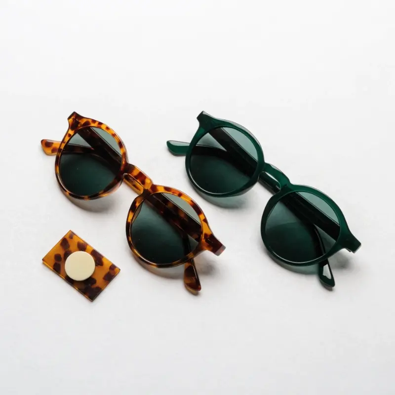 round acetate sunglasses frame shape — tortoiseshell and solid green round frames with acetate sheet sample showing vintage artistic brand positioning