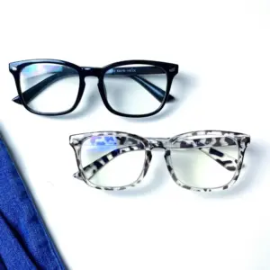 Two blue light glasses with clear lenses showing blue-purple surface reflection — black square frame and grey tortoiseshell square frame on white background
