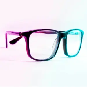 Square frame glasses with clear lenses lit by purple and teal dual-color lighting against a white background, creating a gaming aesthetic