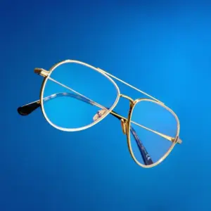 Gold metal double-bridge aviator blue light glasses with clear blue-tinted lenses against a deep blue gradient background