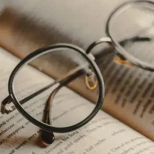 Round wire-frame reading glasses resting on an open book, illustrating diopter strength selection for reading glasses brands