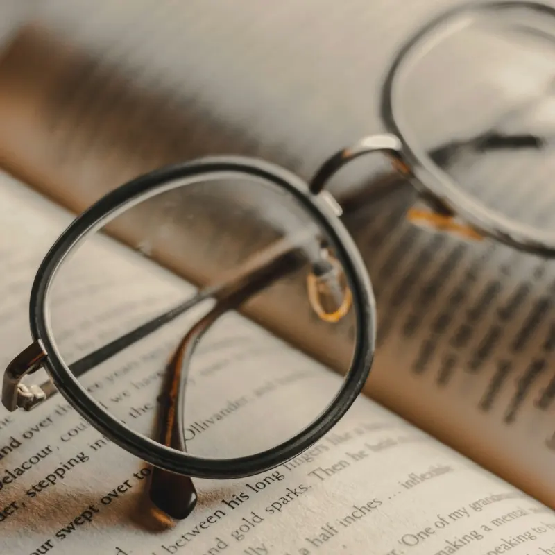 Round wire-frame reading glasses resting on an open book, illustrating diopter strength selection for reading glasses brands