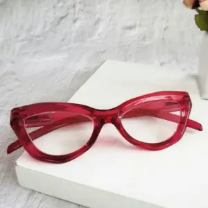 Bold red translucent cat-eye acetate reading glasses on a white pedestal, representing retail pricing strategy for a design-led reading glasses line
