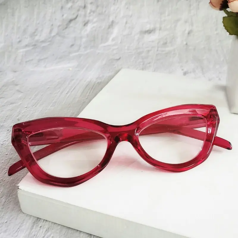 Bold red translucent cat-eye acetate reading glasses on a white pedestal, representing retail pricing strategy for a design-led reading glasses line