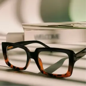 Bold black and tortoiseshell acetate reading glasses displayed beside packaging, representing the sample-to-shipment production process for a reading glasses brand