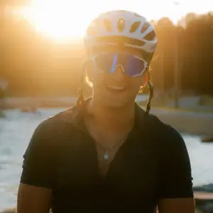 Cyclist wearing sports sunglasses with contrast-enhancing mirrored lens riding at sunset in low light conditions