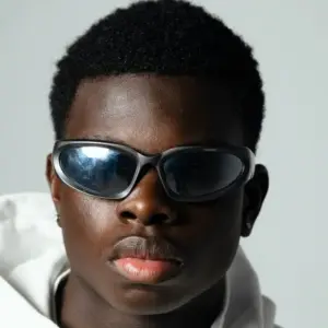 Close-up portrait of a person wearing black wraparound sports sunglasses showing frame material and lens construction