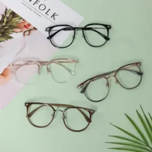 Four pairs of glasses in different frame materials and colors arranged on a light green background — black, clear rose gold, grey metal, and brown tortoiseshell round frames