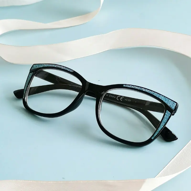Black acetate cat-eye optical frame with glitter-accented temples and printed CE and power markings on the inner temple
