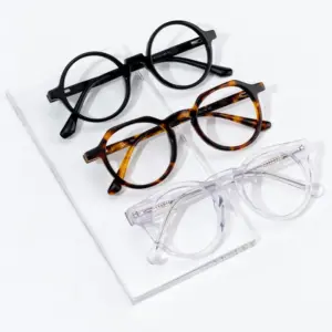 Three round acetate optical frames in black, tortoise, and clear colorways laid flat with visible frame size markings on the temples
