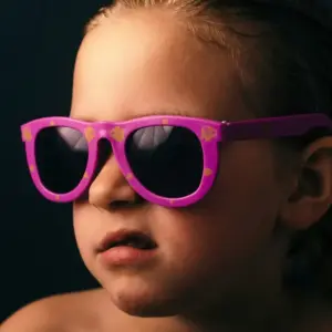Close-up of a toddler wearing pink sunglasses with dark UV-protective lenses, representing safety considerations in children's eyewear