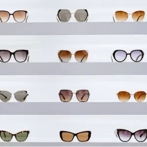 Assorted custom sunglasses styles displayed on a shelf, showing the range of frame shapes and colors that affect manufacturing cost