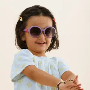 Young girl wearing purple round sunglasses sized to fit her face, illustrating proper bridge and temple fit for kids' eyewear