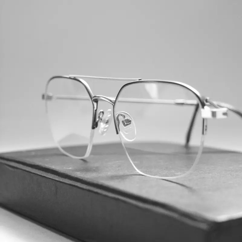 Close-up of a semi-rimless metal optical frame showing hinge and rimless lens edge construction